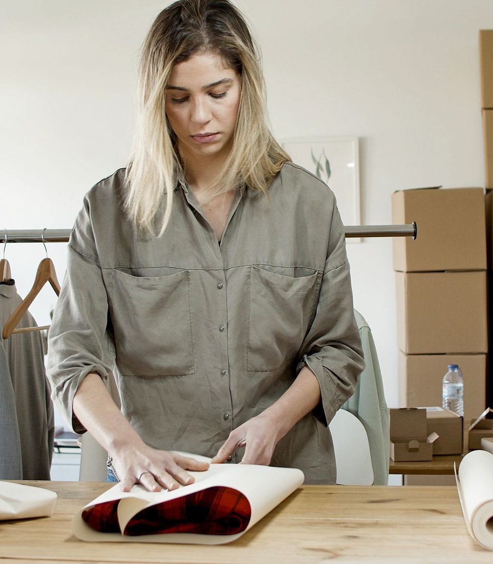 A woman wrapping a garment in paper to post to a customer