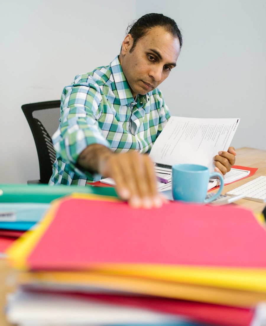 A business owner reading a document beside a pile of coloured folders