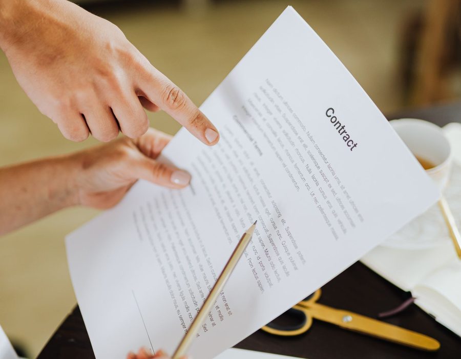 Two people pointing at clauses on a printed contract