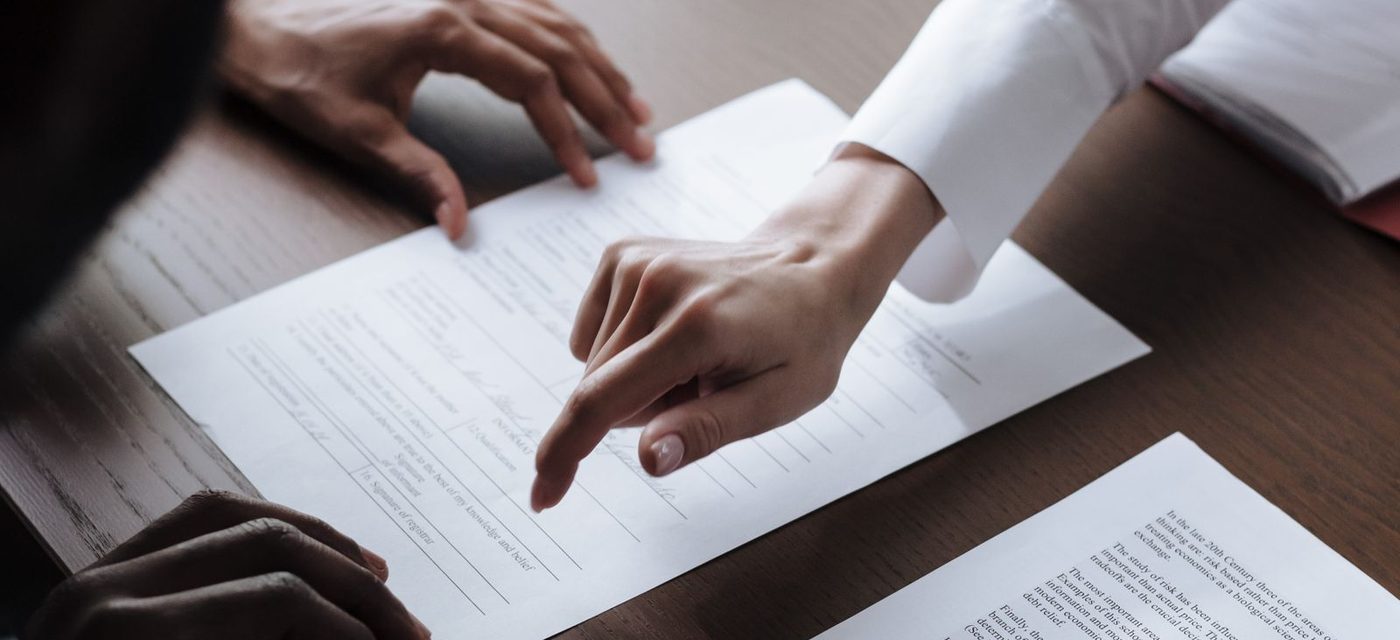 Two people going through a printed contract at a meeting table