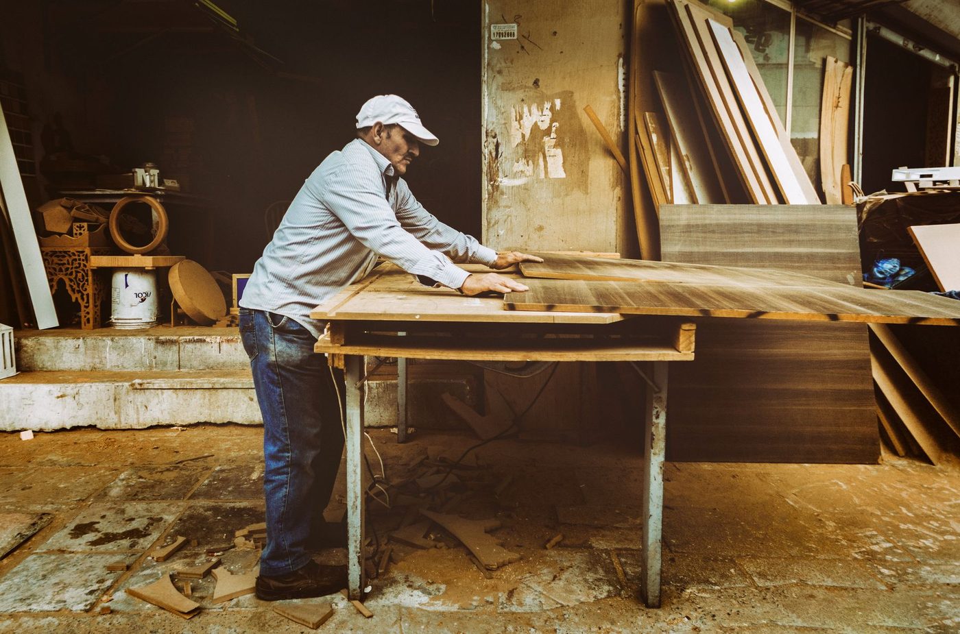 A joiner lining up a long timber board in a busy workshop