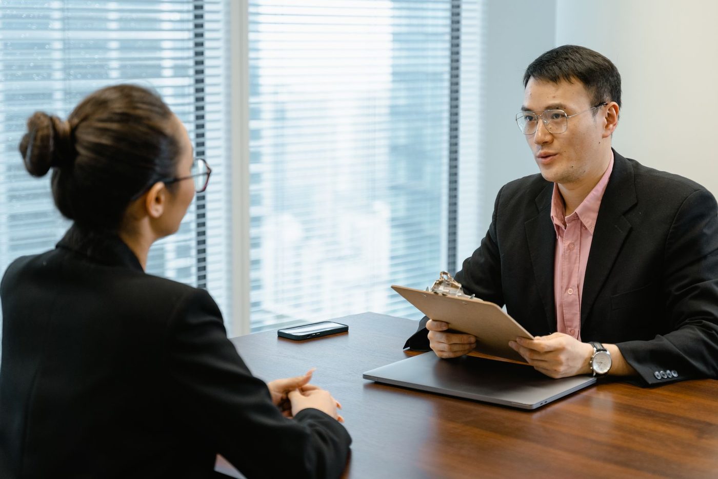 A manager holding a clipboard in a meeting with a member of staff