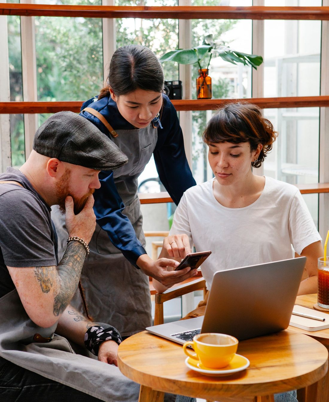 A cafe owner and two staff going over something on a laptop at a table