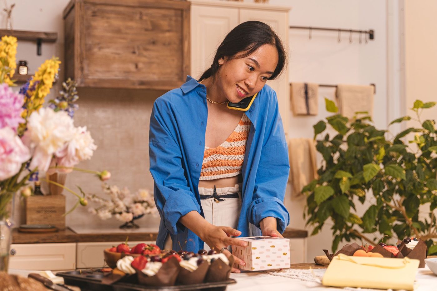 A bakery owner on the phone while boxing an order at her counter