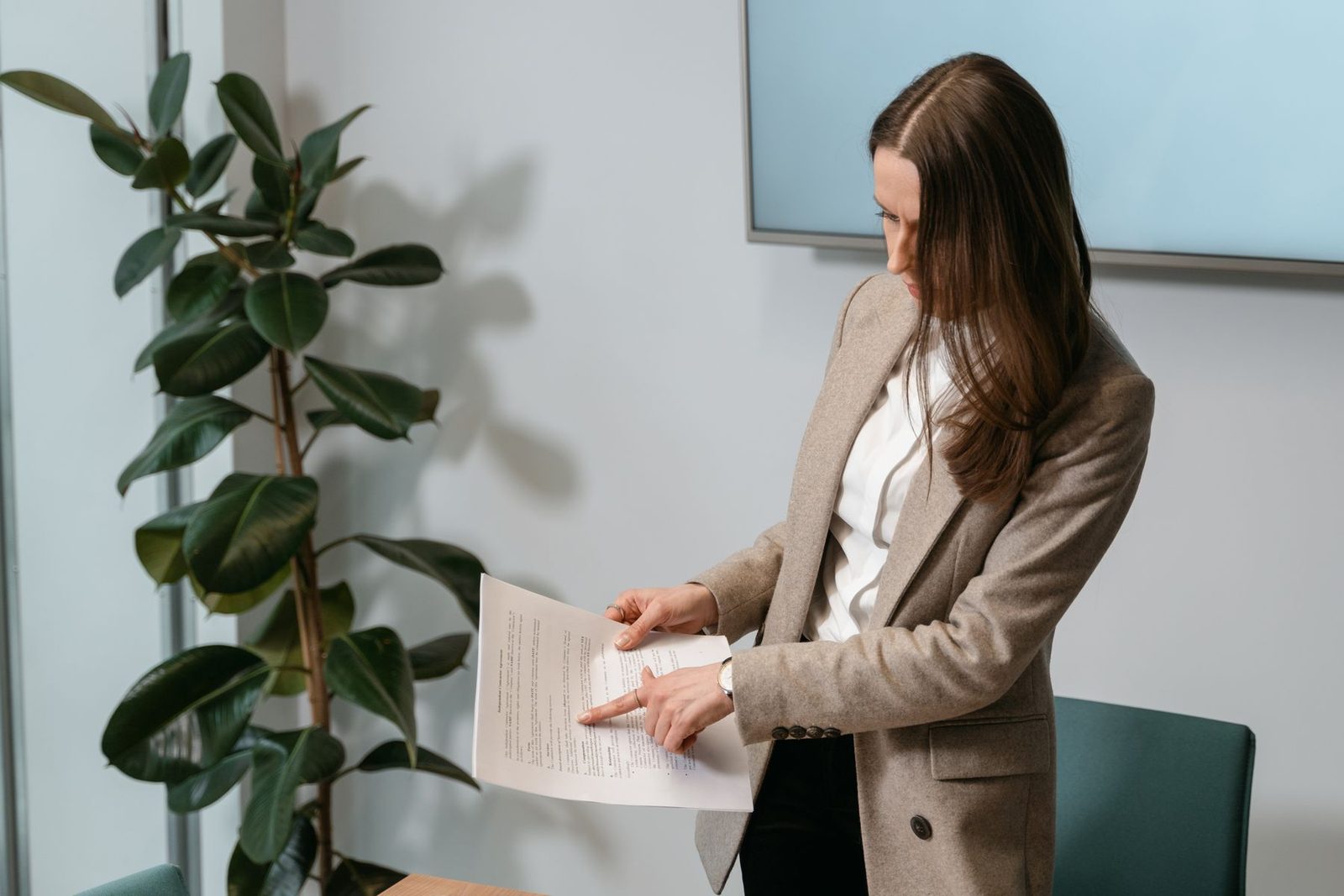 A manager in a blazer standing at her desk reading a document