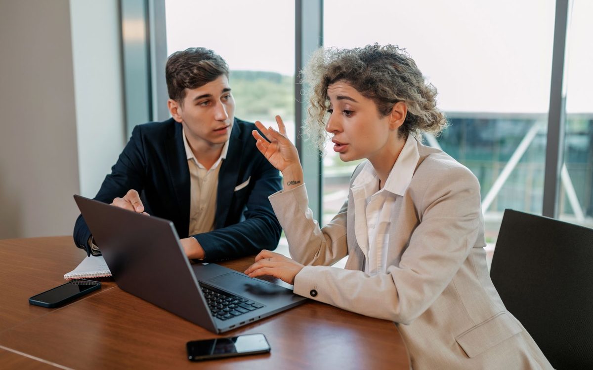 Two business owners talking through a document on a laptop at a meeting table