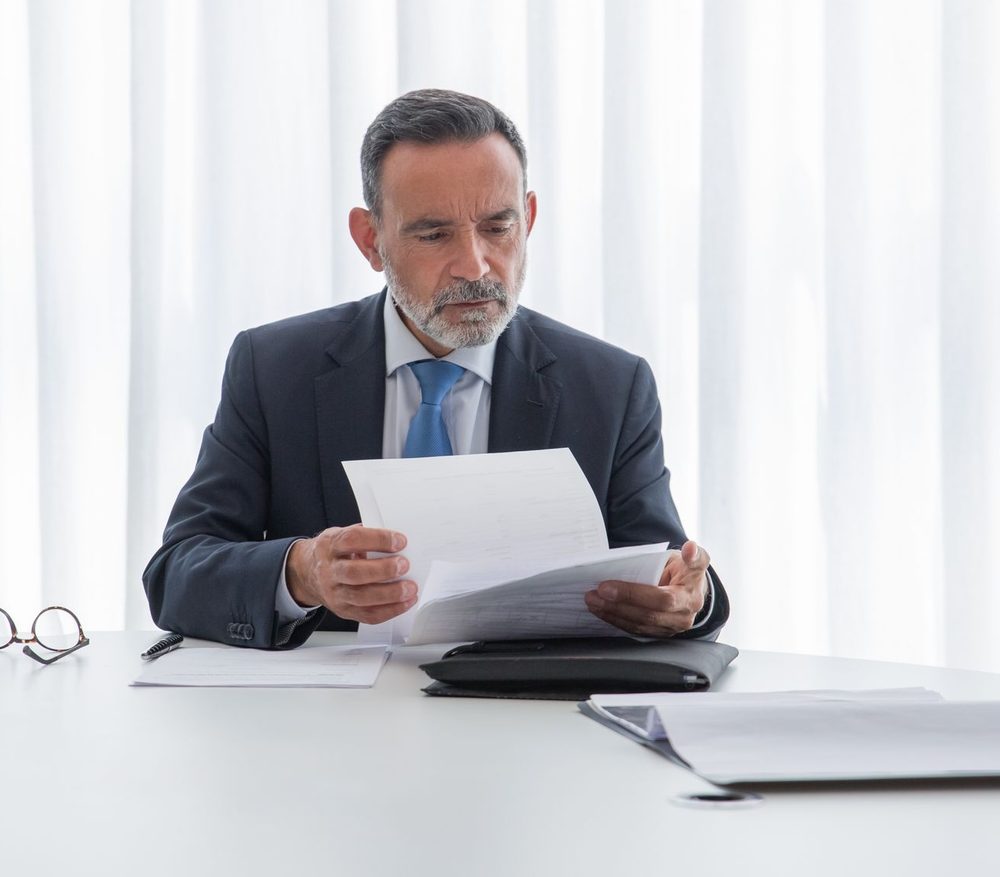 A business owner reading through a set of documents at a white table