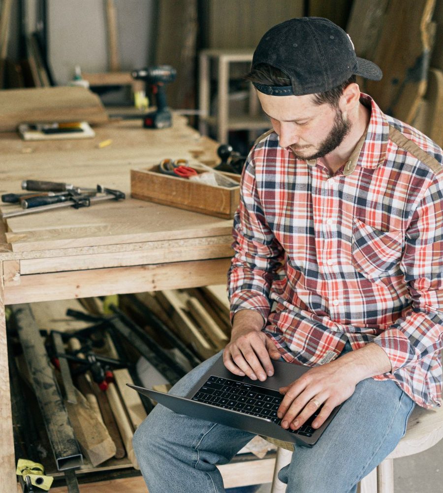 A joiner checking costs on a laptop at his workbench
