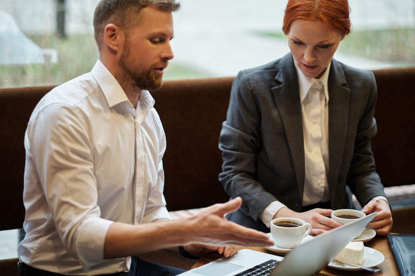 Two people from different businesses going through figures on a laptop over coffee