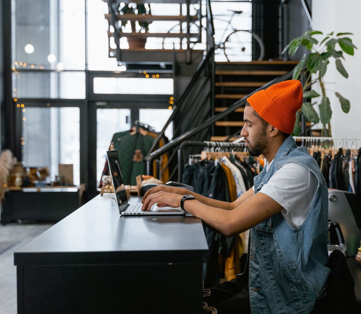 A shop owner working on a laptop at the counter of his clothing shop