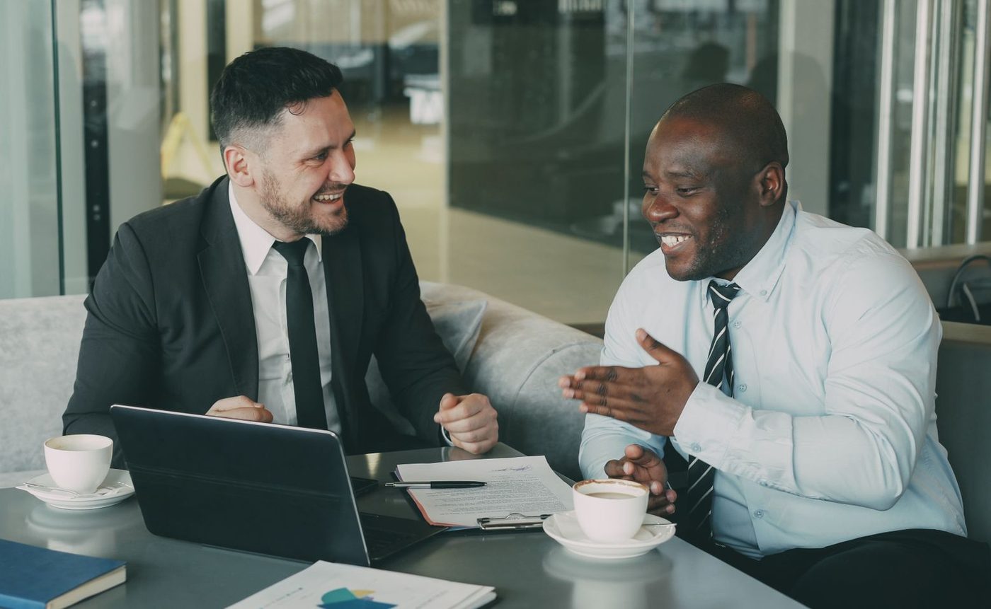 Two business owners talking over coffee and paperwork at a table