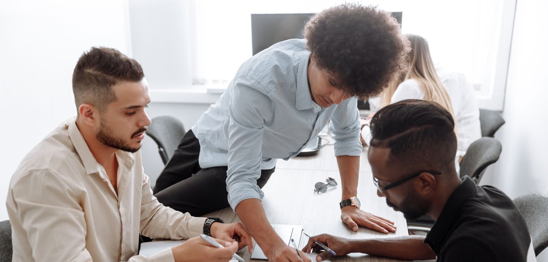 Three colleagues working through plans together at a meeting table
