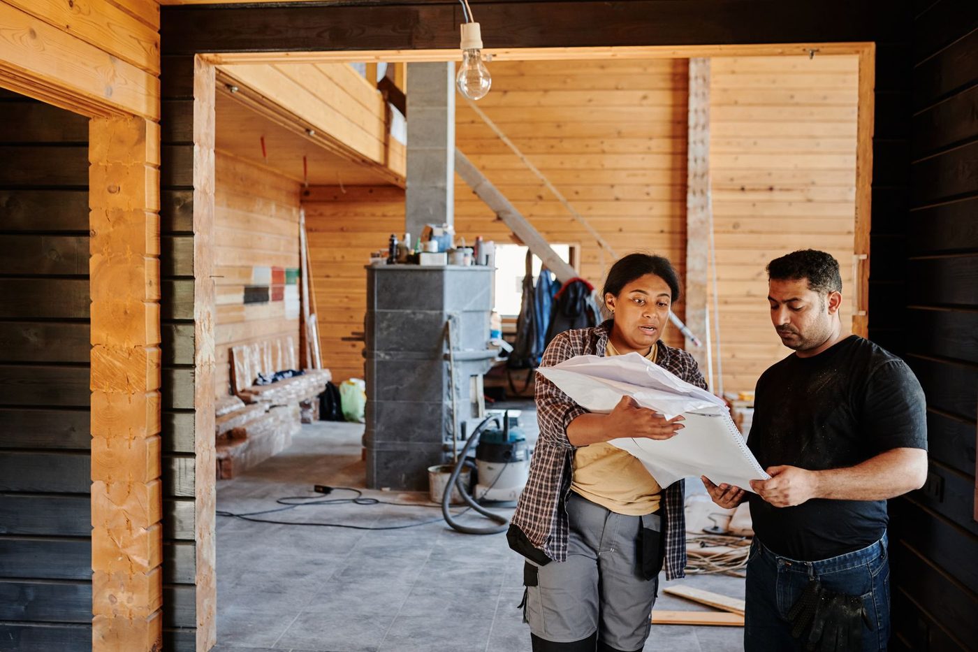 A builder and a customer reading plans together in a house being renovated